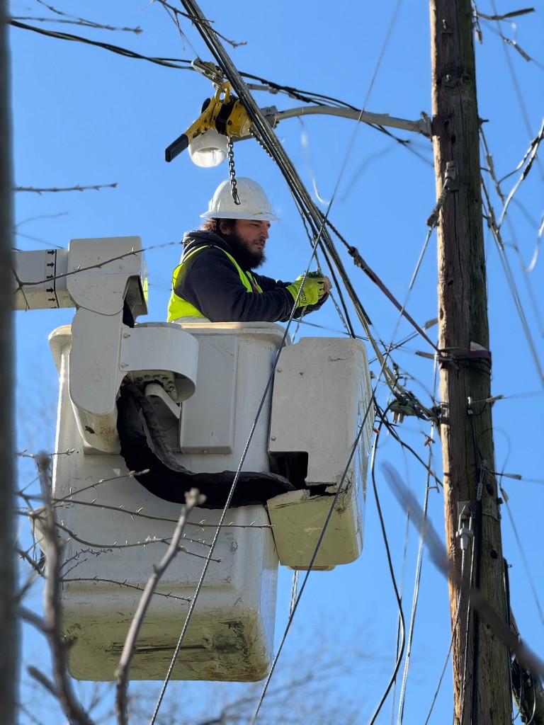 Utility worker in a bucket truck performing overhead line work